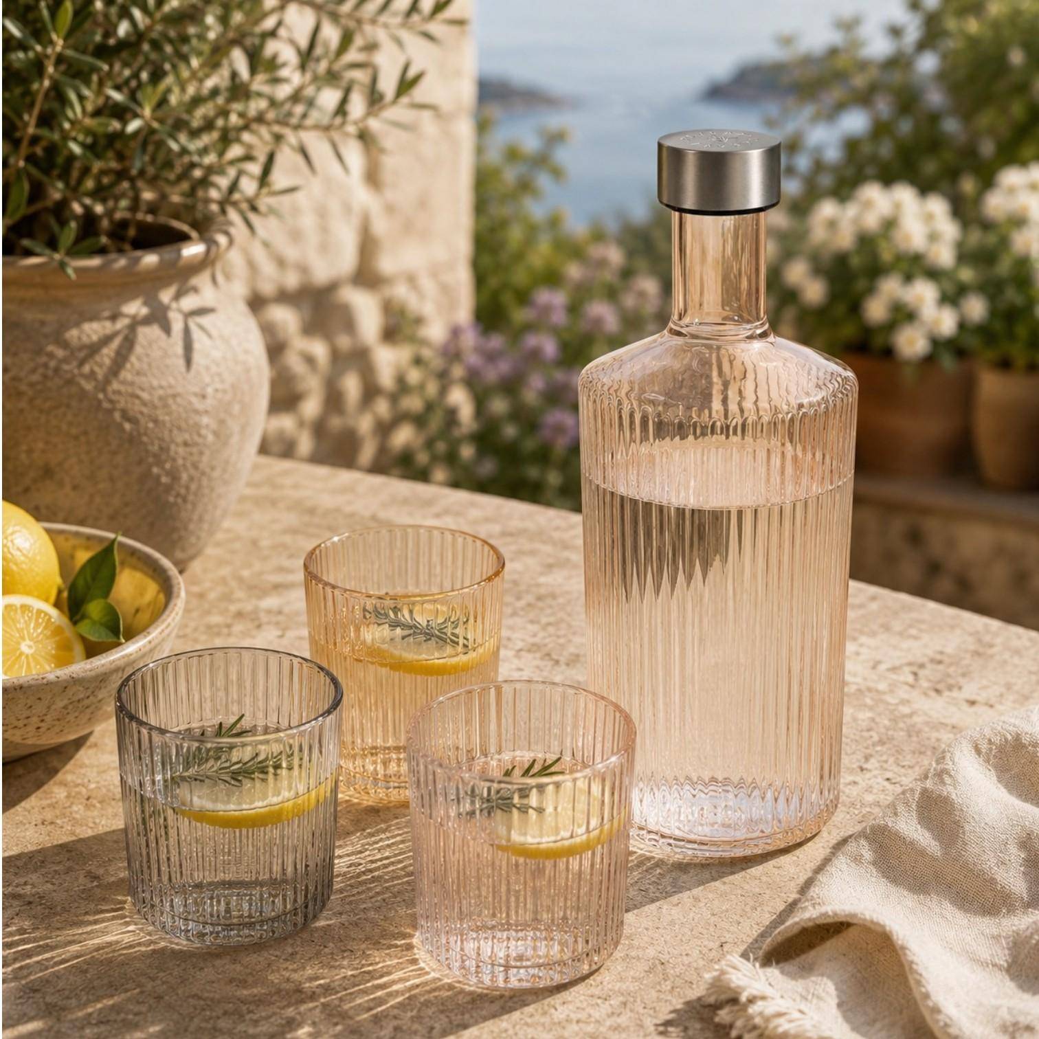 Paveau Ribbed Wasserflasche mit passenden Ribbed Gläsern auf einem sommerlich gedeckten Tisch im mediterranen Ambiente.