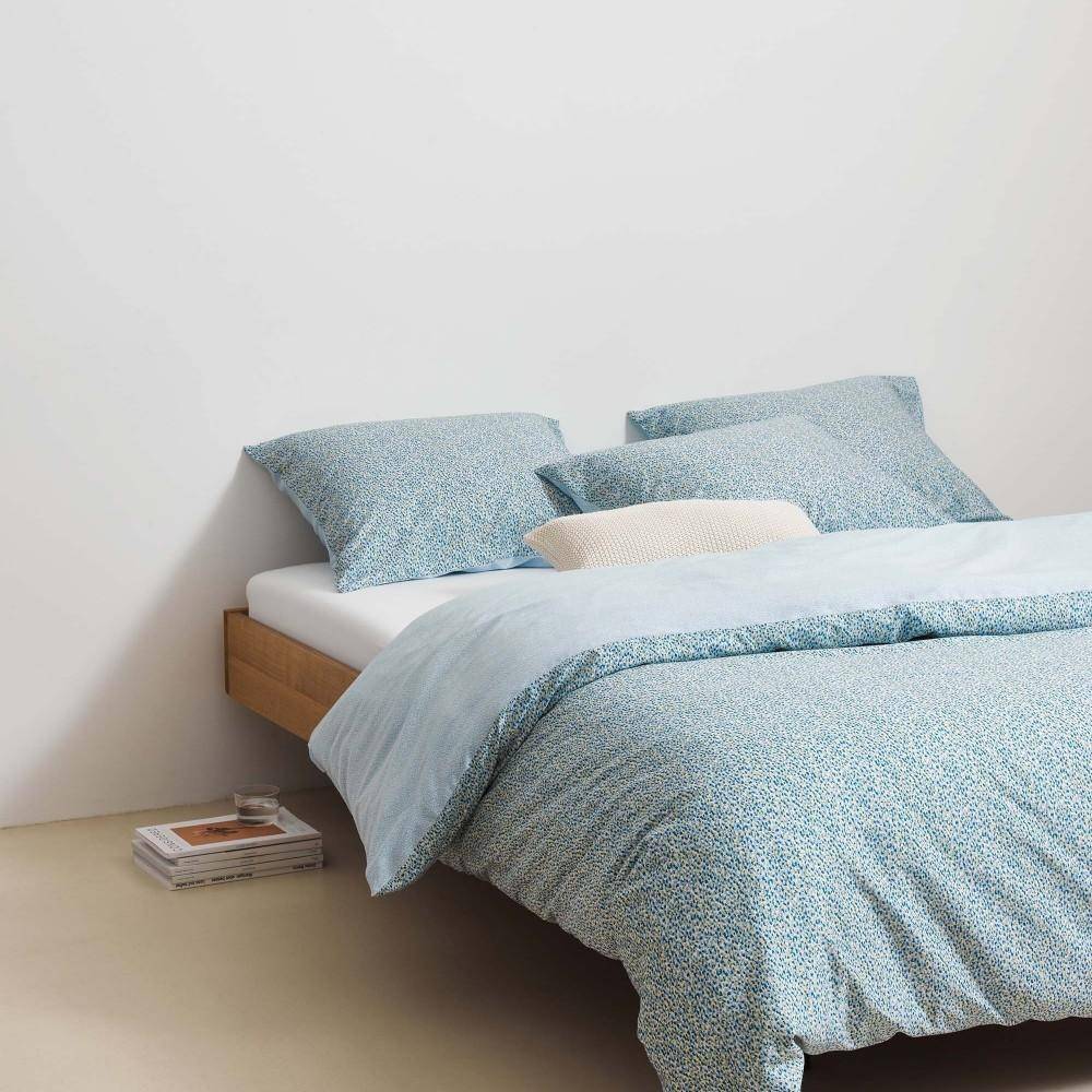 Marc O Polo Dekokissen Nordic Knit Off White auf Bett im Schlafzimmer mit blauer Bettwäsche in modernem Wohnstil