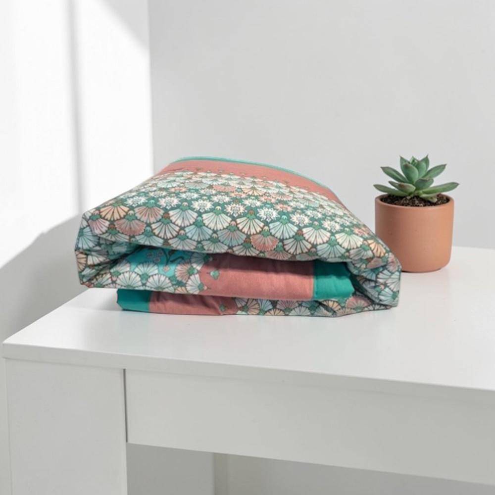 Gefaltetes Bassetti Plaid Tigullio V1 in Aqua Rosa Pfirsich auf Tisch mit floralem Muster