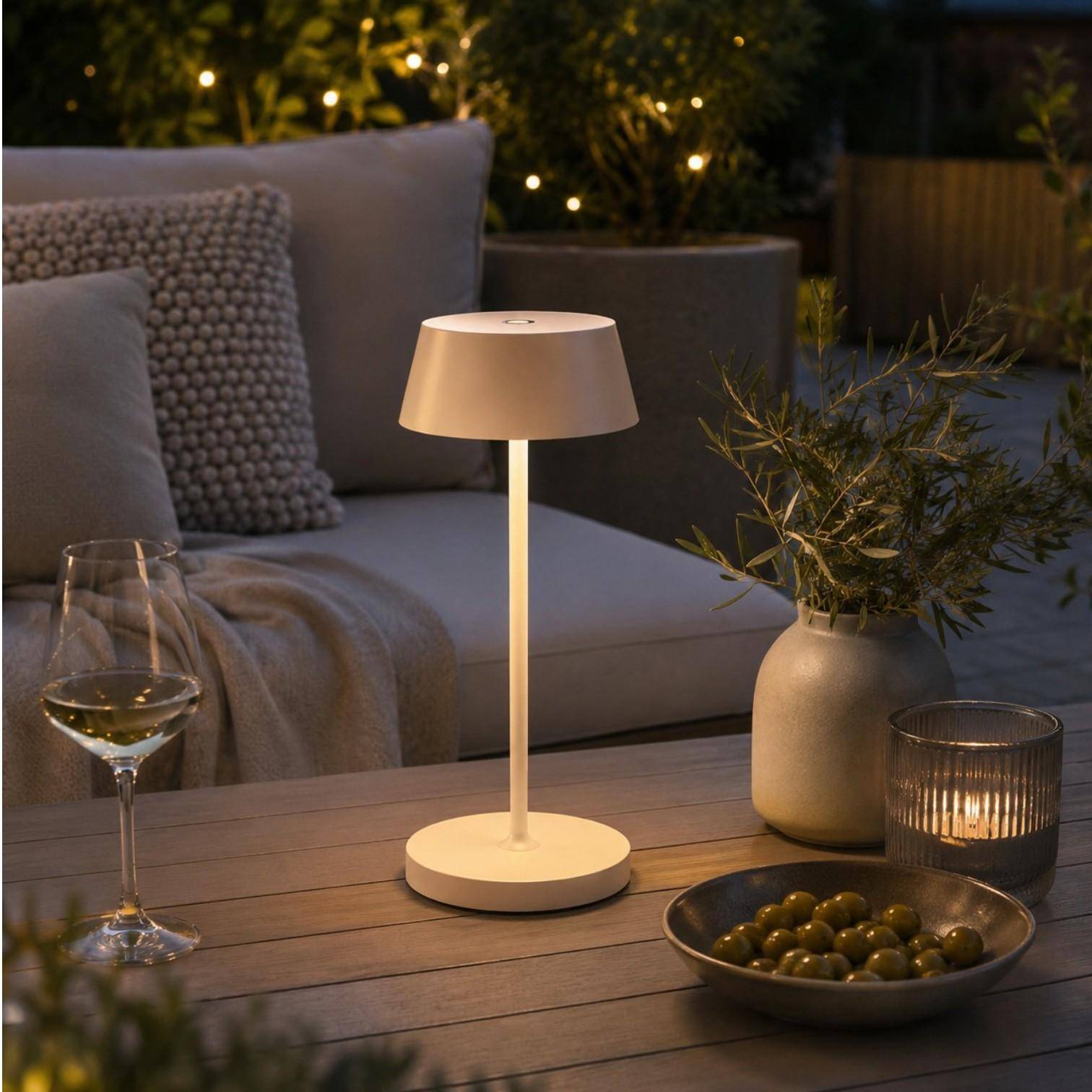 QOOZII Malta kabellose LED Tischlampe in Sand auf einem Holztisch im Garten. Moderne Akku-Tischlampe mit warmweißem Licht für Terrasse, Balkon und Outdoor-Lounge.