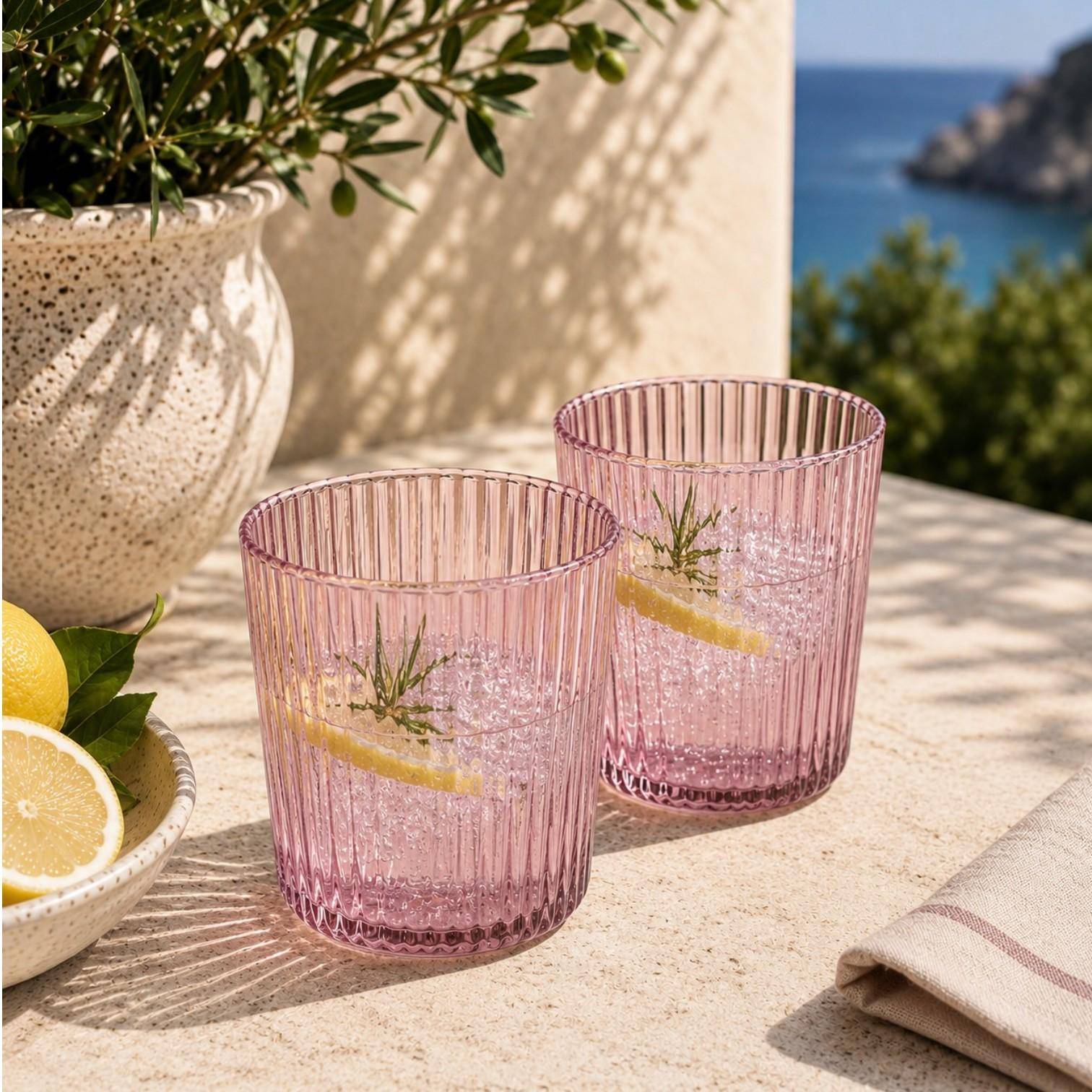 Paveau Ribbed Trinkgläser aus geriffeltem Glas stilvoll gedeckt auf einem sommerlichen Tisch mit Zitronen und Wasser