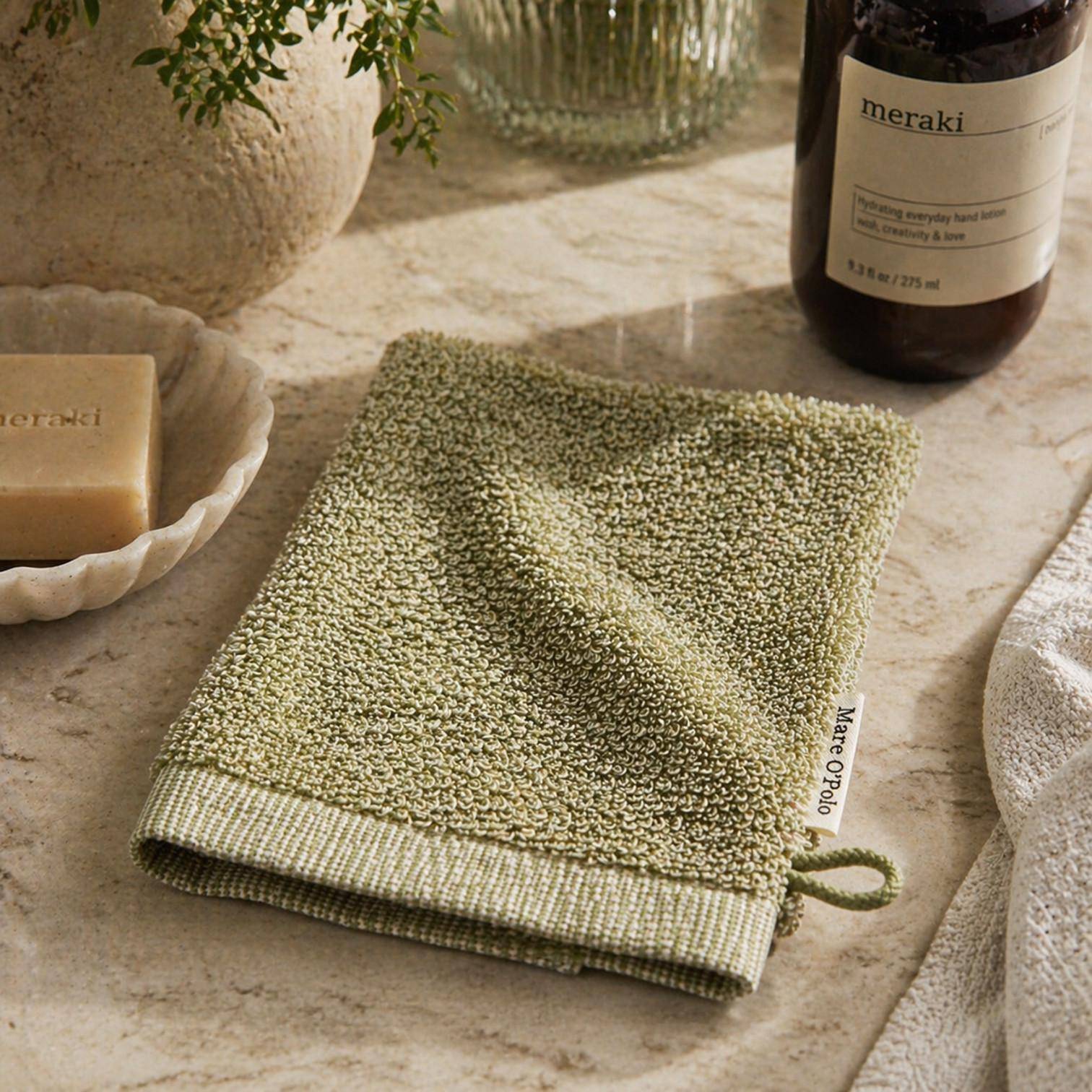 MARC O'POLO Timeless Melange Waschhandschuh in Moss Green im Badezimmer mit Seife und natürlichen Accessoires dekoriert