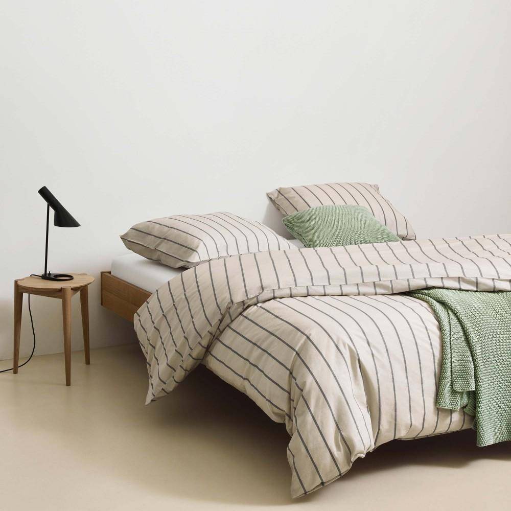 Marc O’Polo Plaid Nordic Knit Garden Green als Strickdecke auf Bett mit gestreifter Bettwäsche