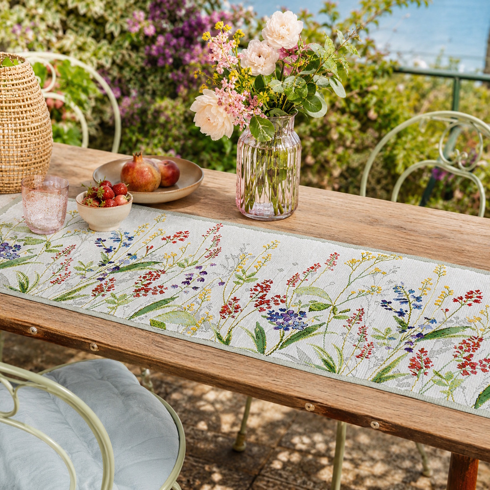 Sander Tischläufer Flower Meadow mit farbenfrohem Wildblumenmotiv auf einem Holztisch im sommerlichen Garten