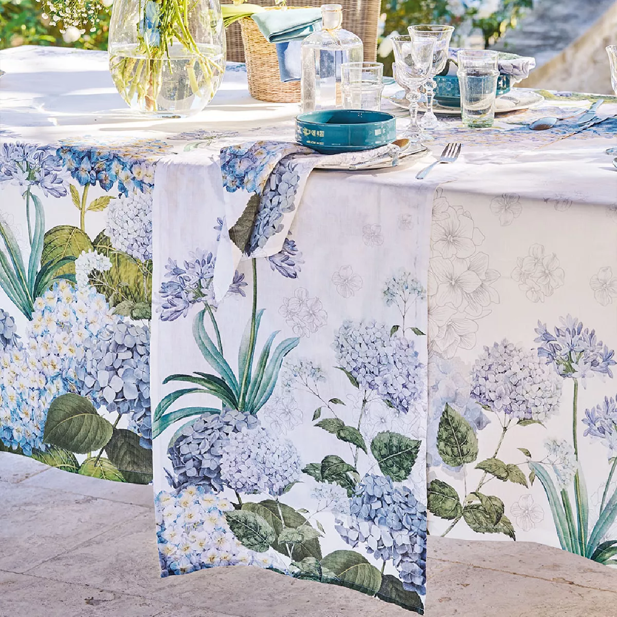 Tischläufer in Weiß mit Hortensienmotiv aus Halbleinen Jardin de Bretagne Bleu von Garnier Thiebaut auf einem Gartentisch