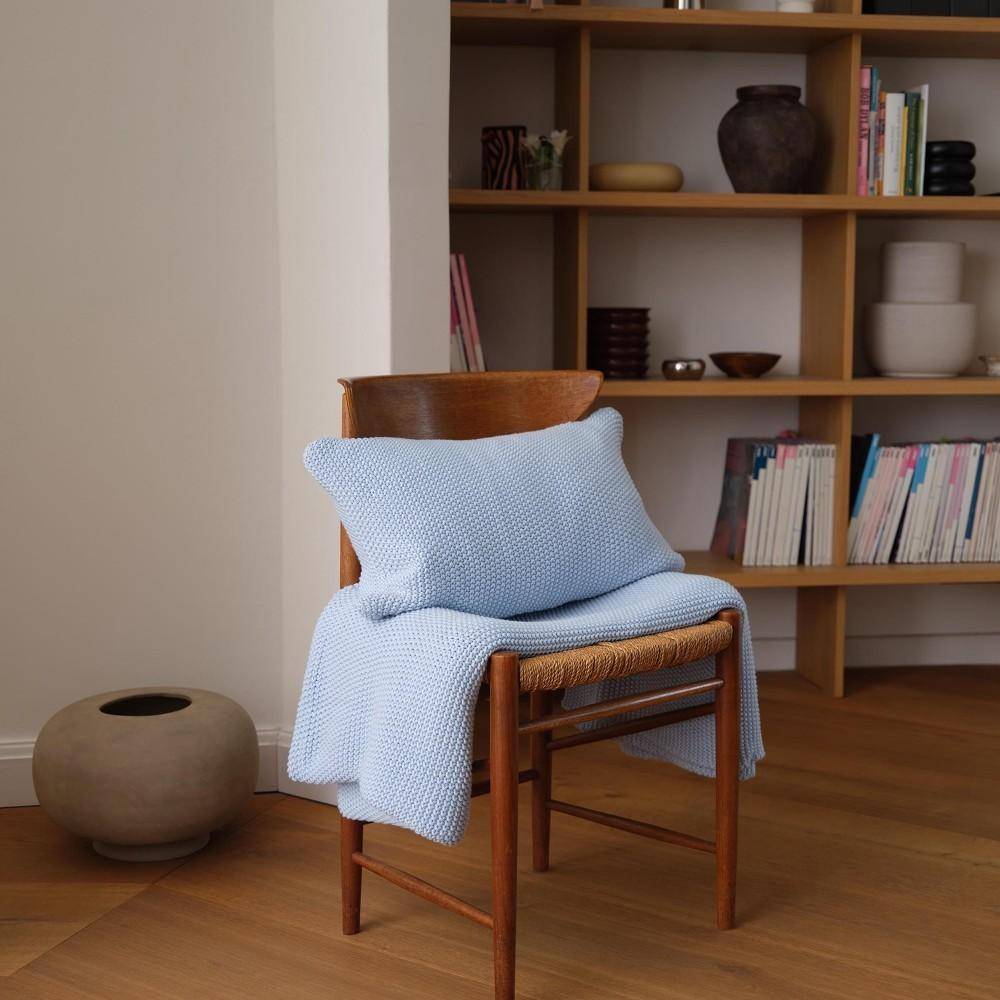Marc O'Polo Dekokissen Nordic Knit Calm Blue auf Holzstuhl im modernen Wohnraum mit skandinavischem Stil