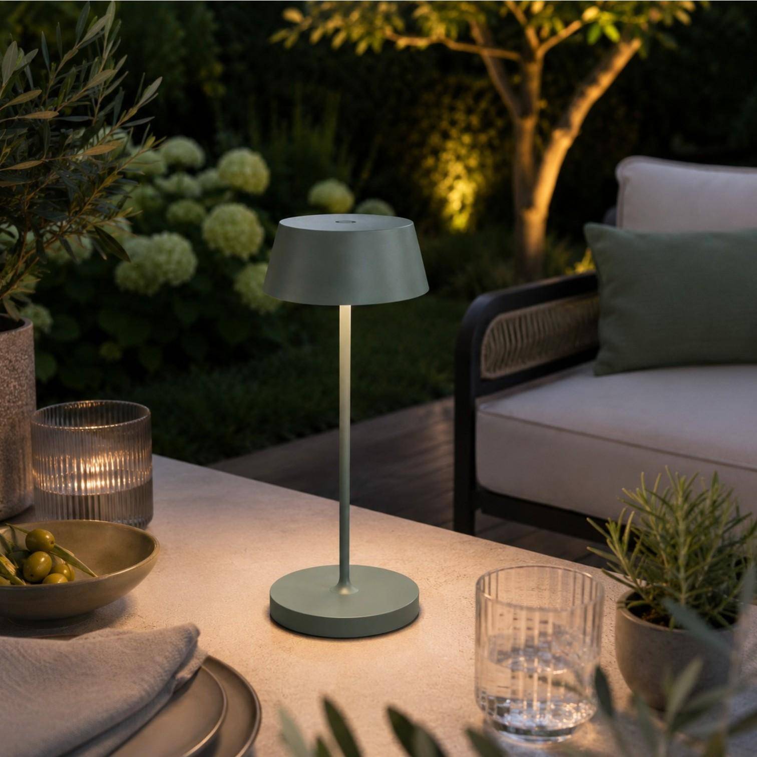 QOOZII Malta kabellose LED Tischlampe in Olive auf einem Holztisch im Garten. Moderne Akku-Tischlampe mit warmweißem Licht für Terrasse, Balkon und Outdoor-Lounge.