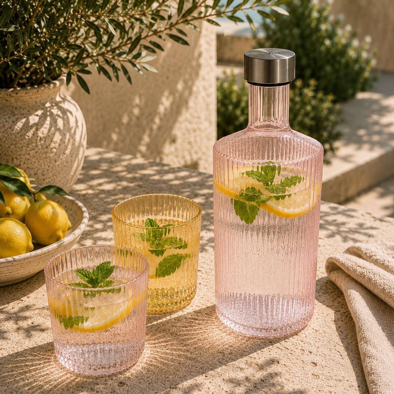 Paveau Ribbed Wasserflasche mit passenden Ribbed Gläsern auf einem sommerlich gedeckten Tisch im mediterranen Ambiente.