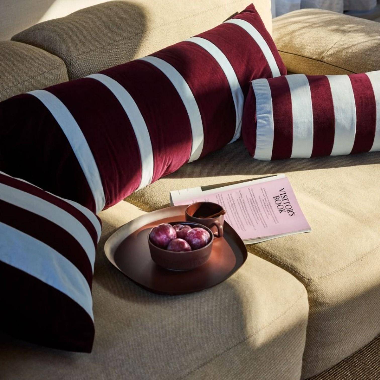 ESSENZA Nackenrolle Bell Mauve Wine 22 x 50 cm als elegantes Streifenkissen auf modernem Sofa